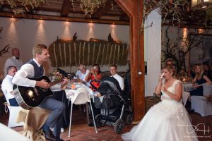 Braeutigam singt ein Staendchen fuer seine Braut. Der Hochzeitsfotograf macht die Fotos.